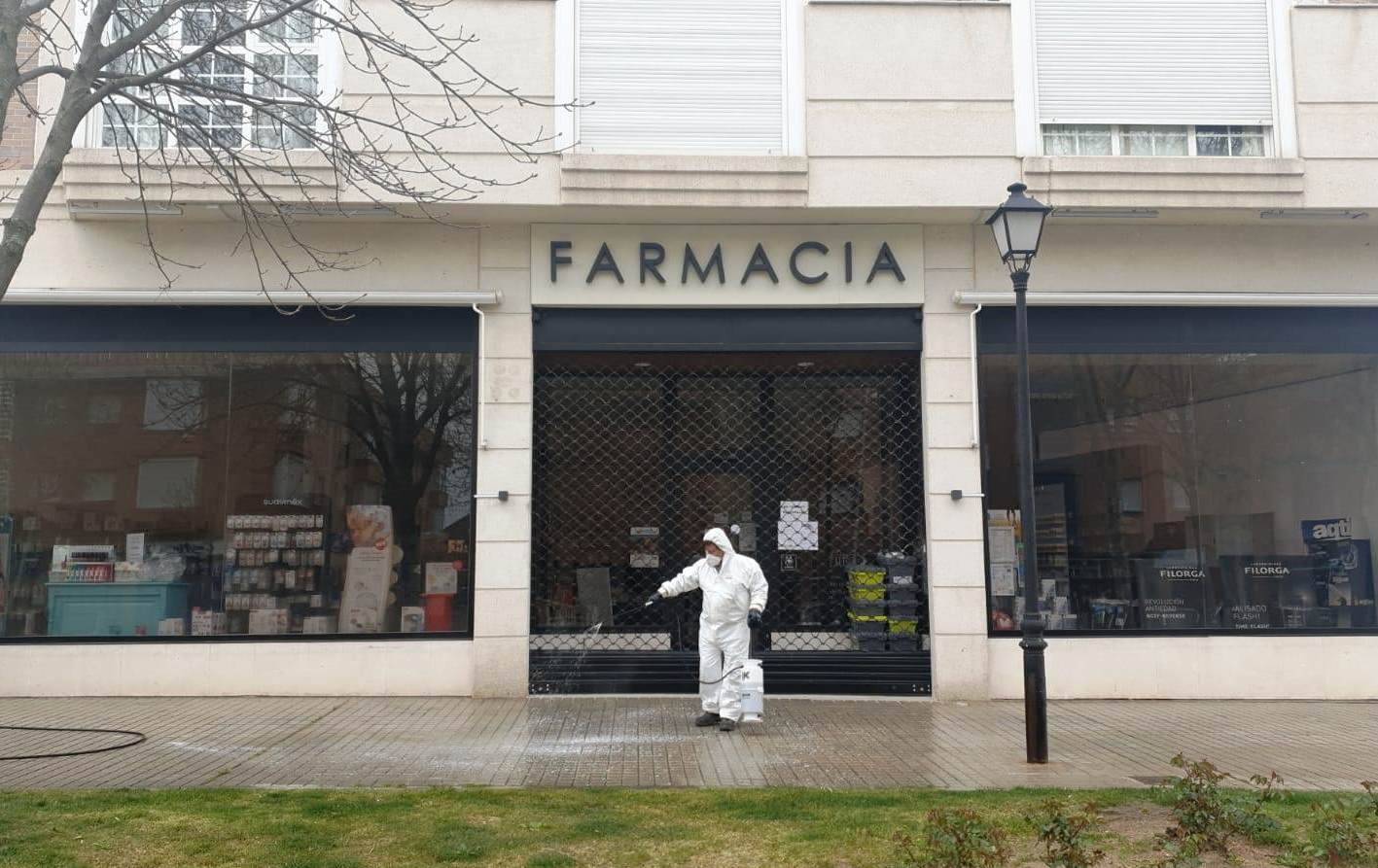 Operario de limpieza delante de una farmacia.