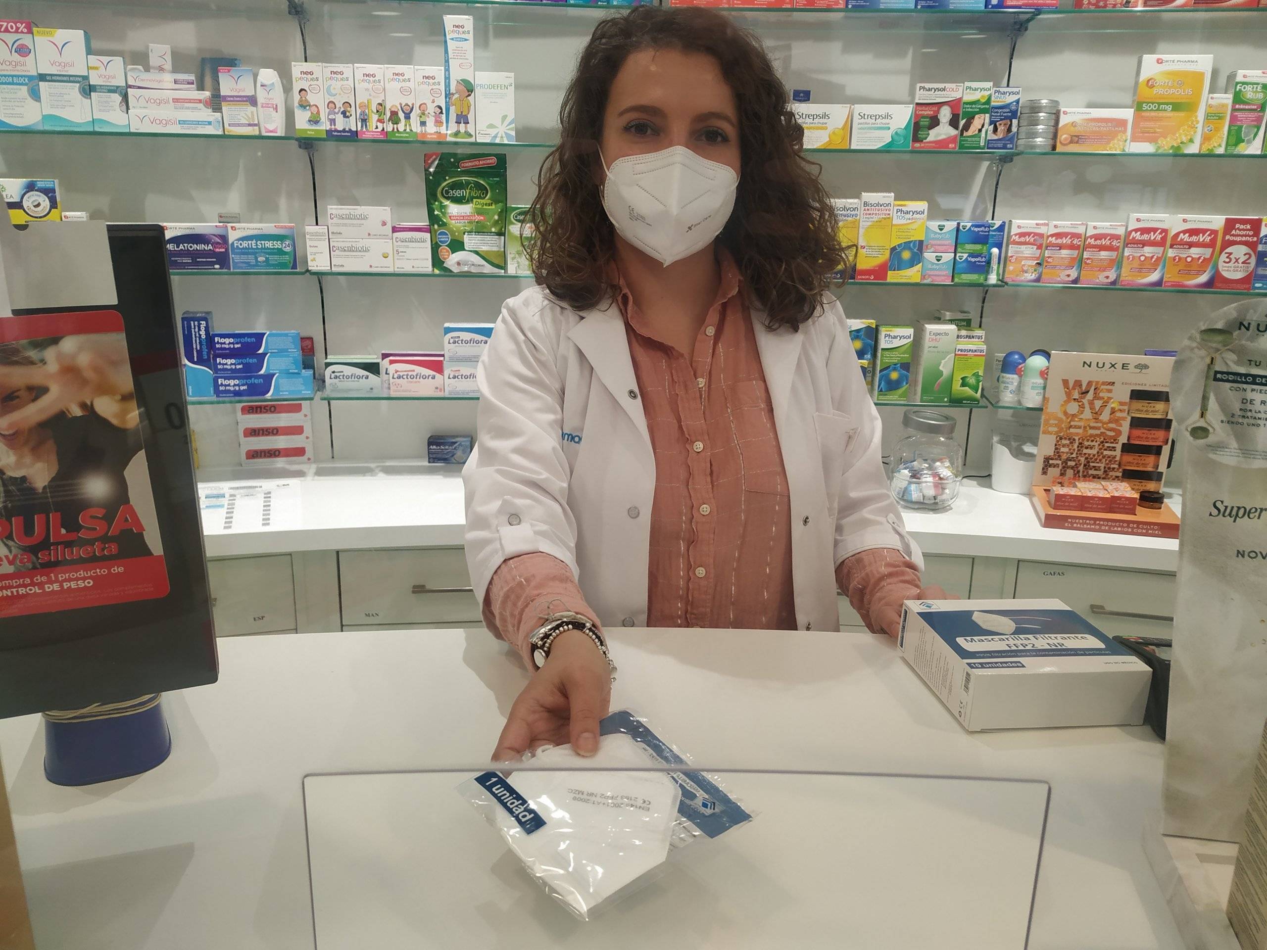 Una farmacéutica del municipio entregando una mascarilla.