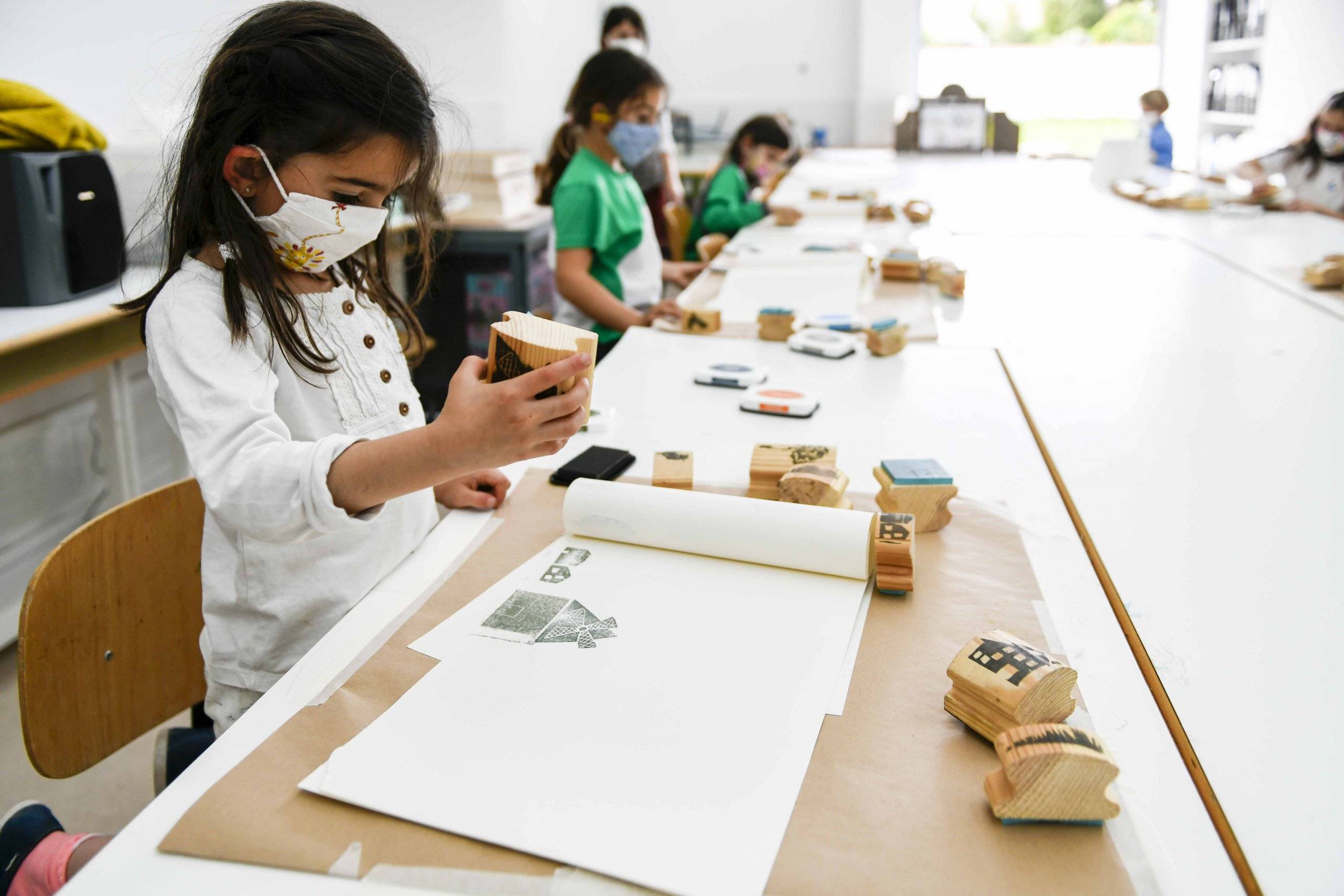 Grupo de niños utilizando la técnica de estampación e impresión de sellos sobre papel.