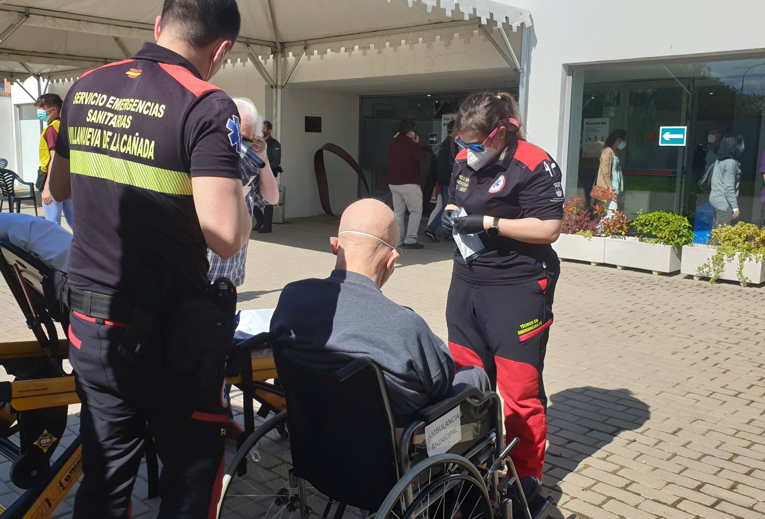 Técnicos del Servicio Municipal de Emergencias Sanitarias trasladan en silla de ruedas a una persona con movilidad reducida al colegio electoral.