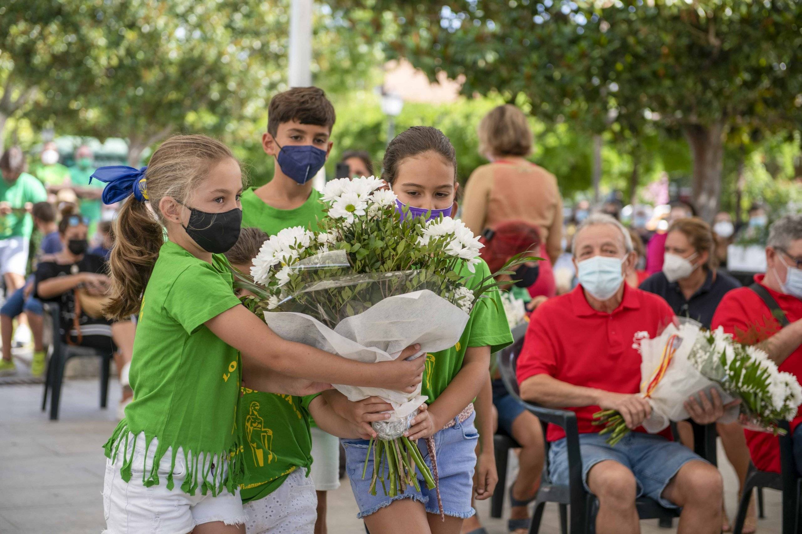 Varios niños de la peña Los Despernaos portando un ramo de camino al altar.