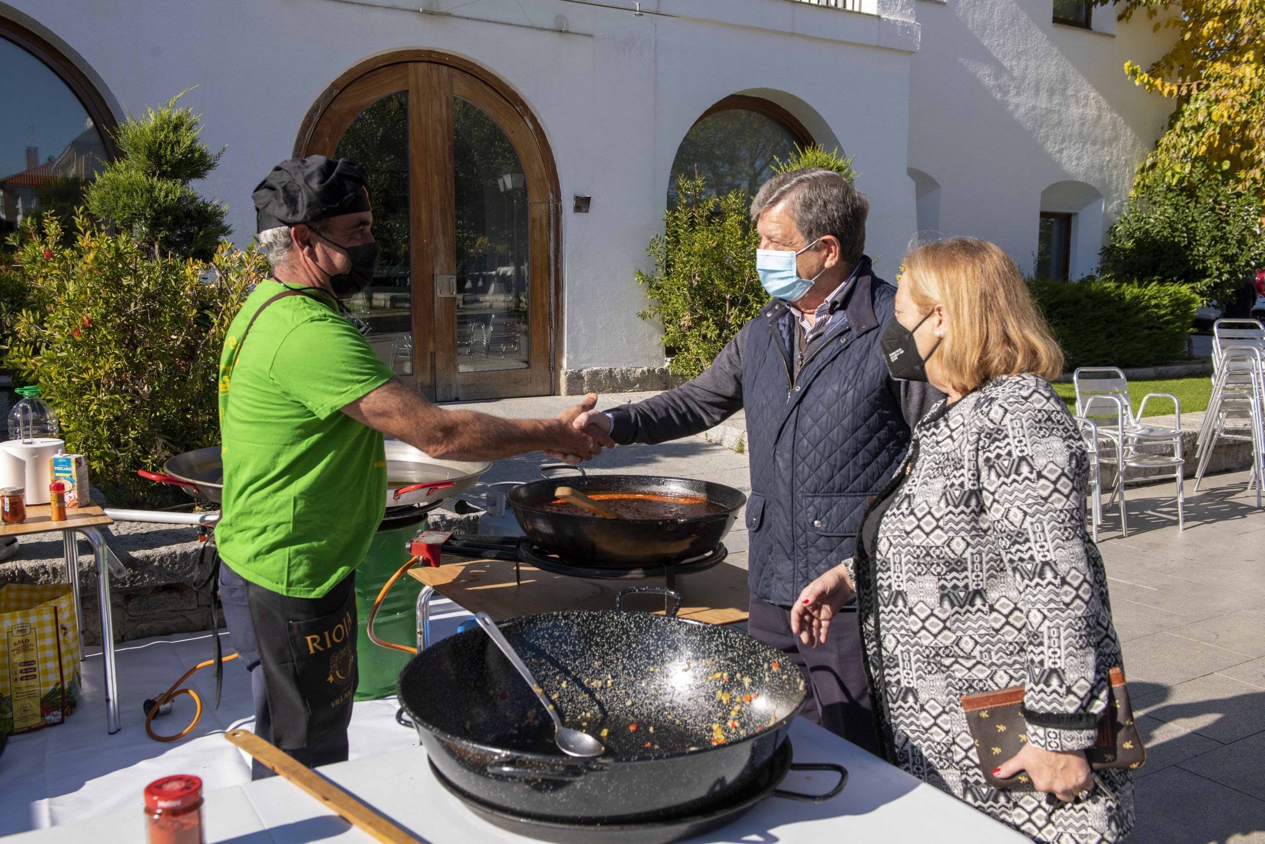 El alcalde saluda a un miembro de la peña Los Despernaos que colabora en el mercadillo solidario.