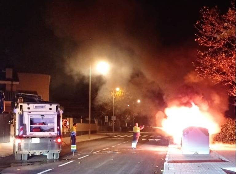 Operarios municipales apagando un incendio en un contenedor del municipio.