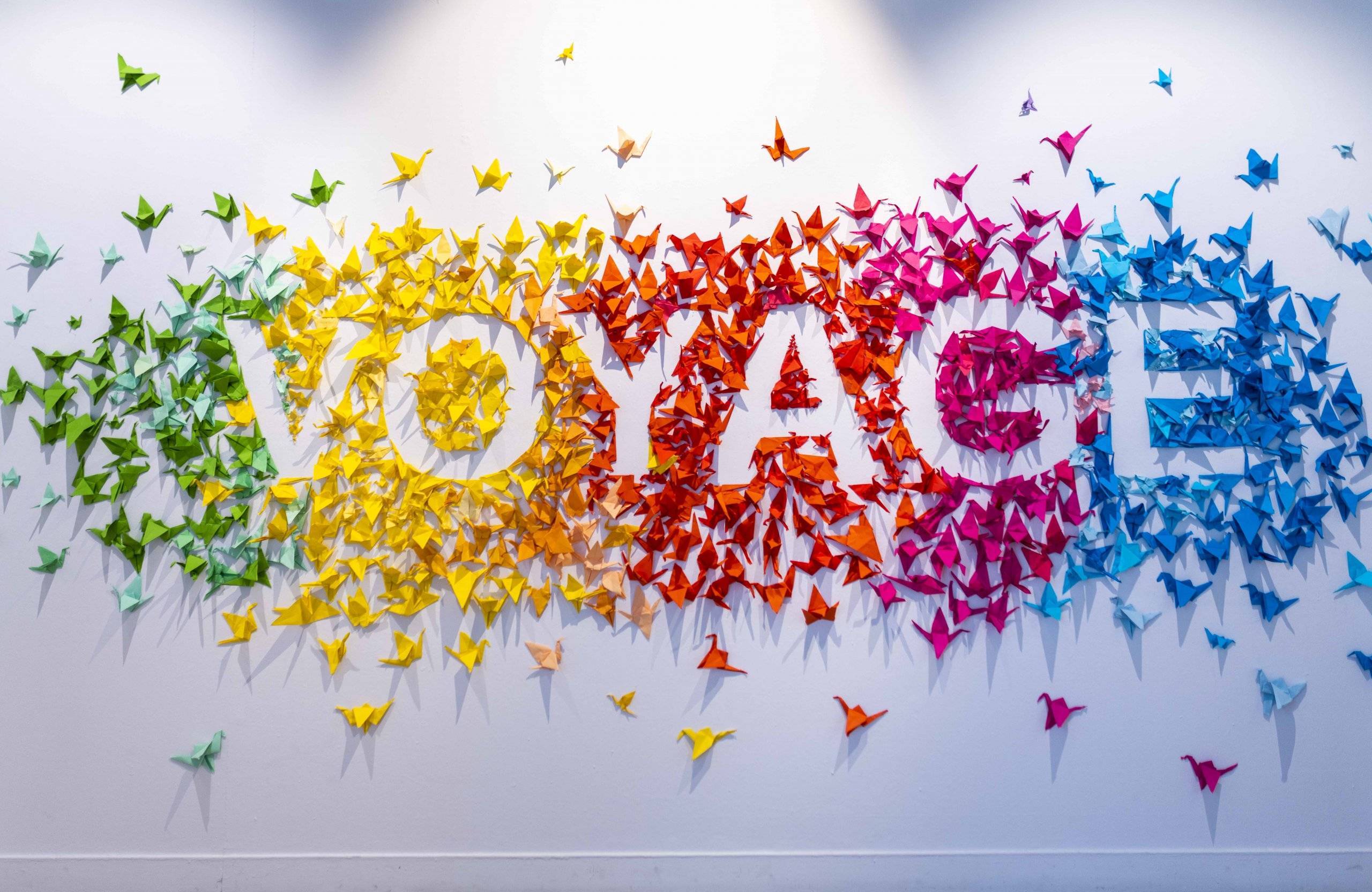 La palabra "Voyage" realizada con pajaritas de papel.