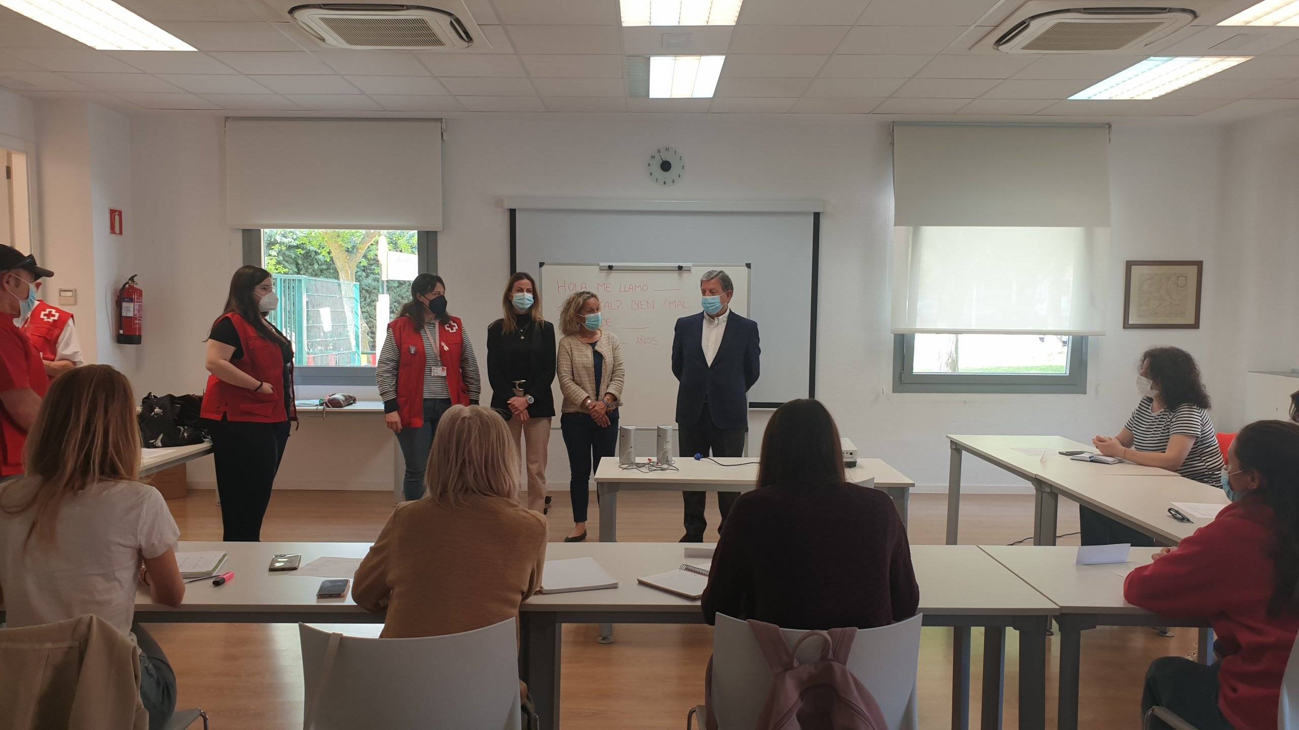 Autoridades locales y miembros de Cruz Roja en un aula junto a alumnos.