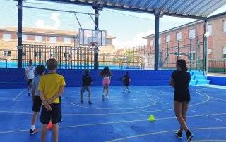 Niños participantes en el Minicampus de verano jugando al baloncesto.