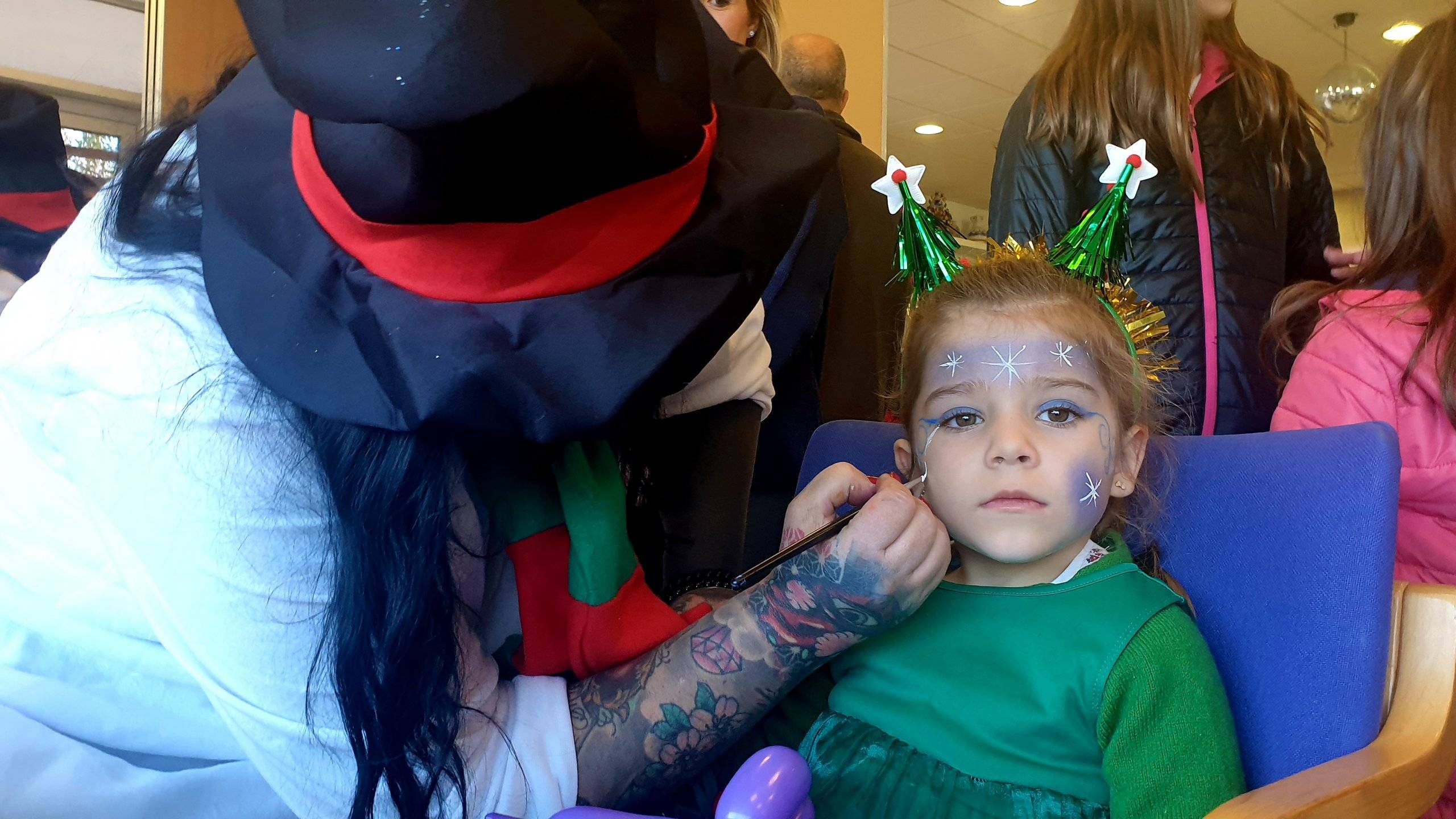 Elfa navideña pintando la cara a una niña.