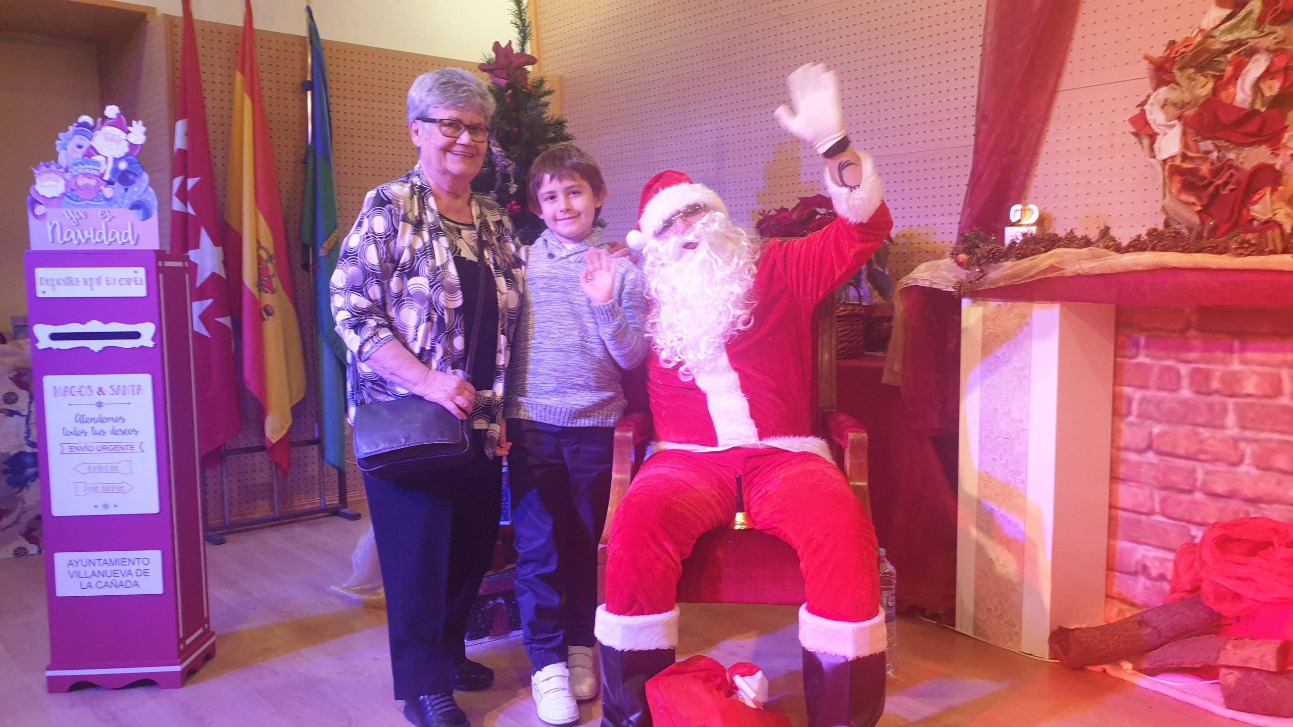 Papá Noel saluda junto a una abuela y su nieto.