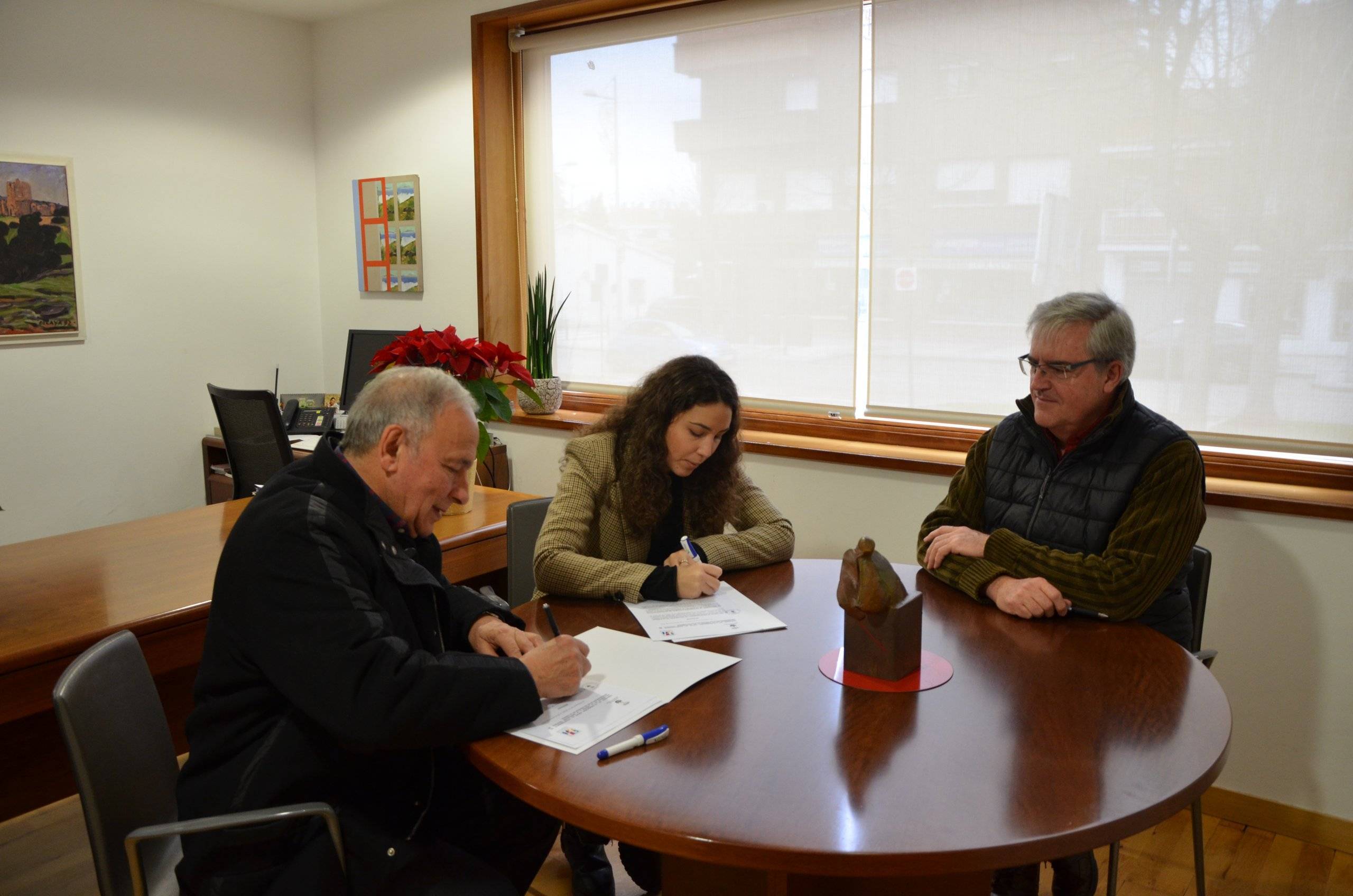 La concejala de Hermanamientos junto al presidente y vicepresidente de la ACH sentados en una mesa durante la firma.