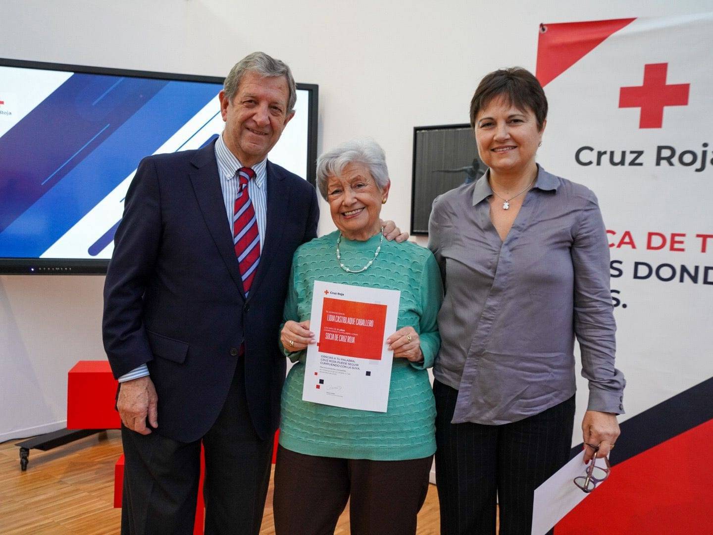 El alcalde y la directora comarcal entregando reconocimiento a una socia de Cruz Roja.