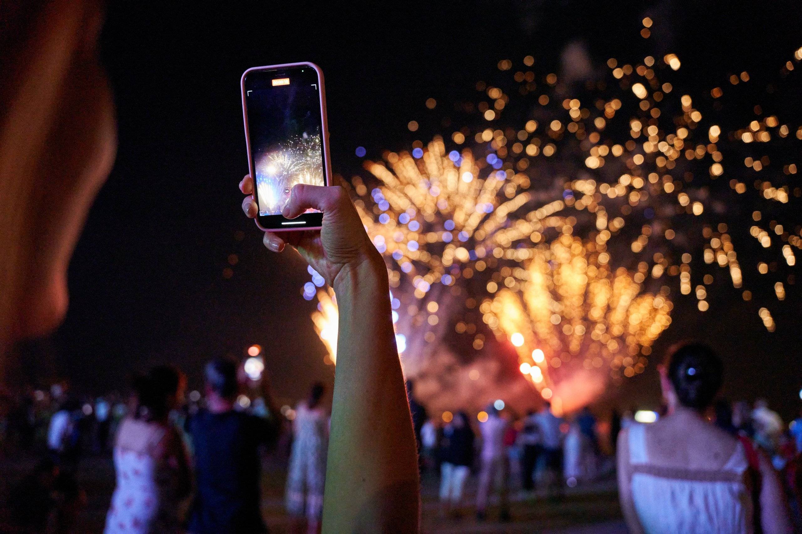 Mano grabando con el móvil los fuegos artificiales.