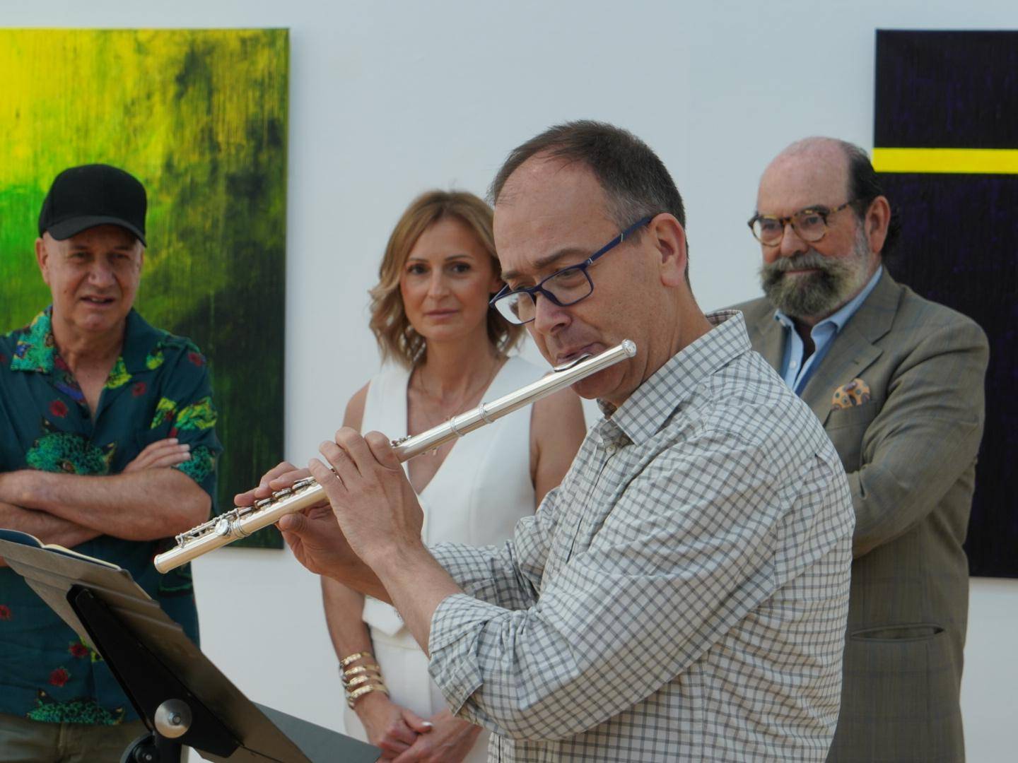 El concejal de Cultura, Fernando Agudo, la pintora Laura Mateo y el hermano del artista José Miguel Velázquez Chena observan la actuación de un profesor de la EMMD Villanueva de la Cañada.
