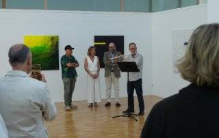 El concejal de Cultura, Fernando Agudo, la pintora Laura Mateo y el hermano del artista José Miguel Velázquez Chena observan la actuación de un profesor de la EMMD Villanueva de la Cañada.