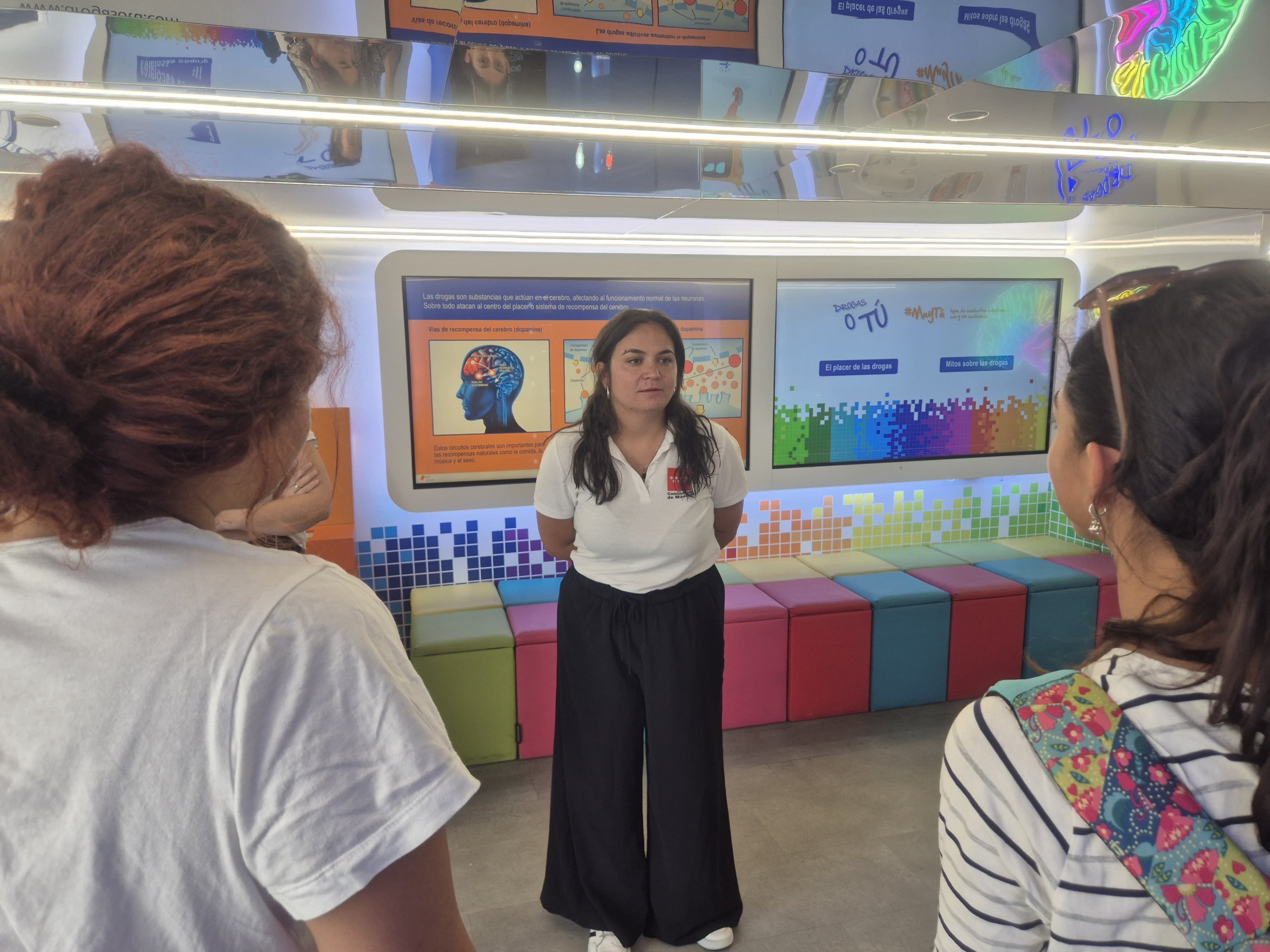 Educadora de pie hablando con dos jóvenes.