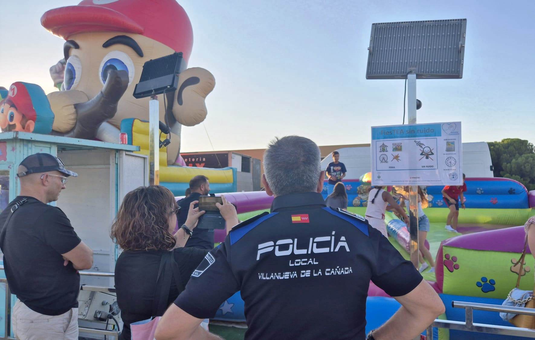 Primer plano policía de espaldas, al fondo atracción infantil