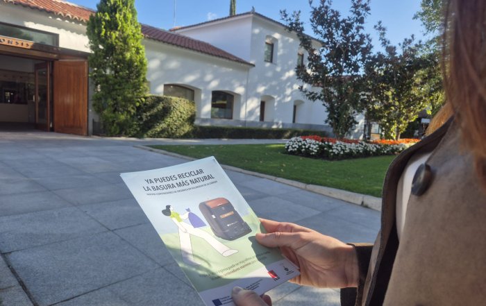 Una persona sujetando un díptico donde se lee "Ya puedes reciclar la basura más natural"