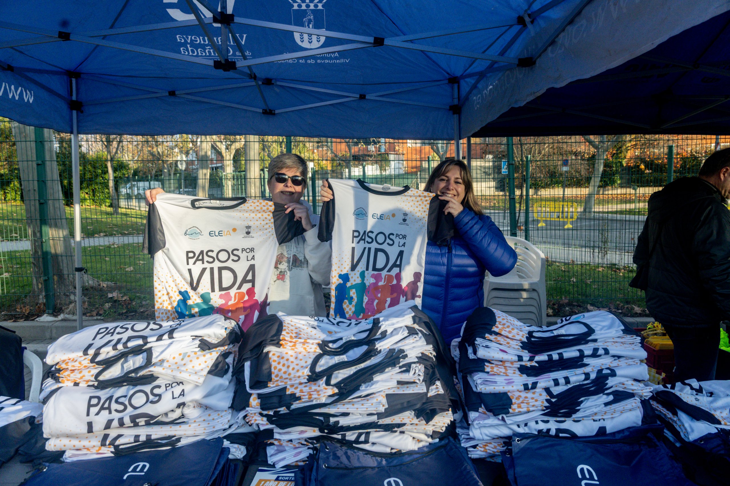 Dos voluntarias muestran las camisetas con el lema de la carrera.