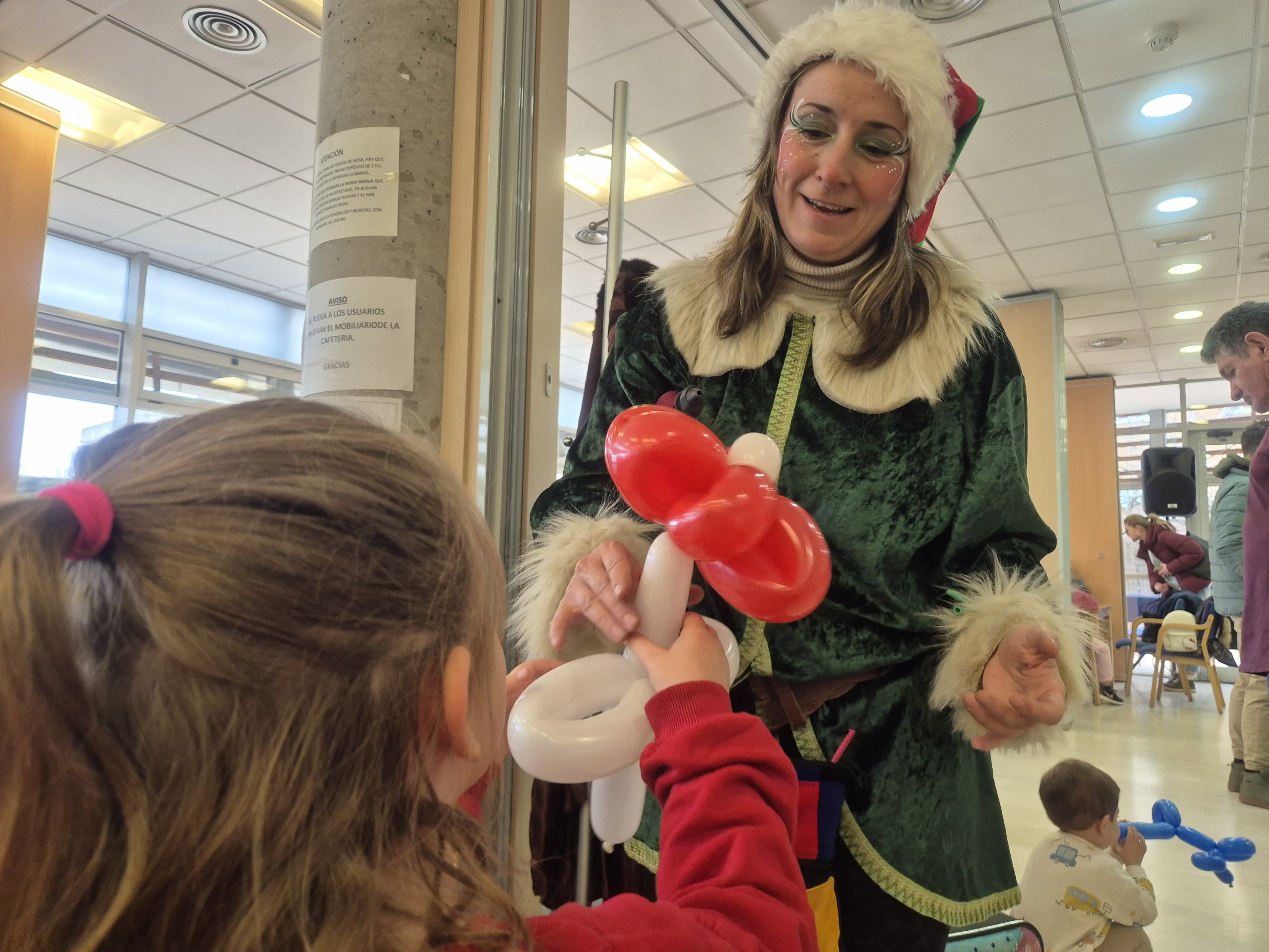 Una elfa entregando una flor de globo a una niña.