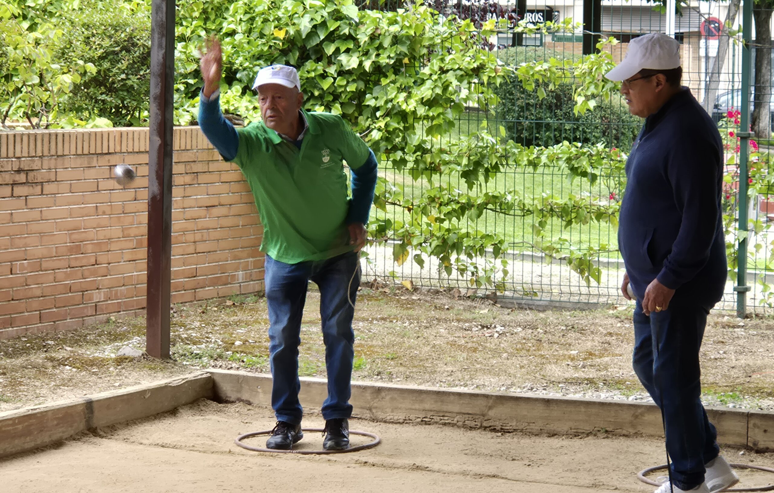 Participante en el Torneo de Petanca lanzando una bola.