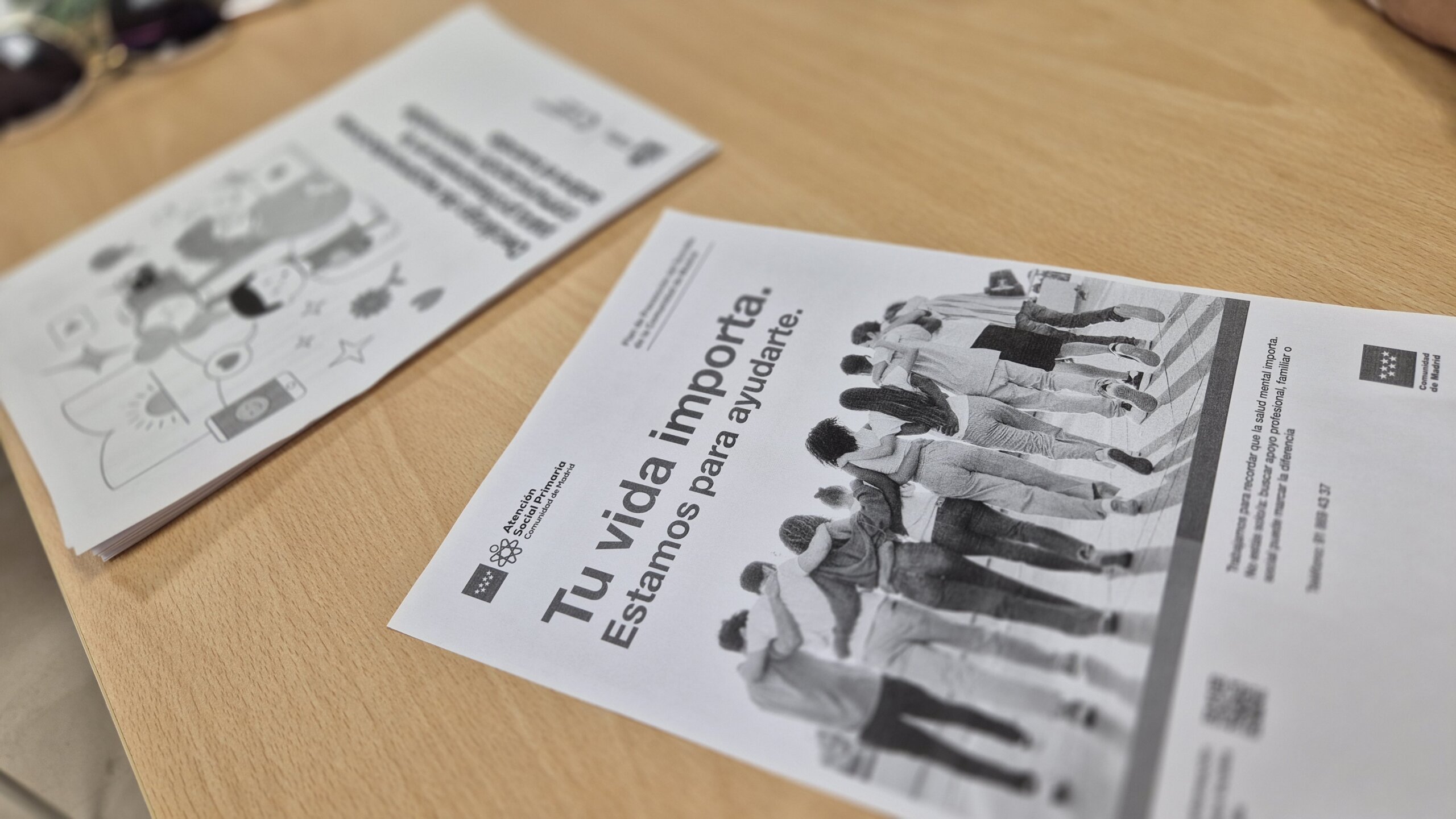 Cartel sobre una mesa con imagen de jóvenes y el texto: "Tu vida importa. Estamos para ayudarte"