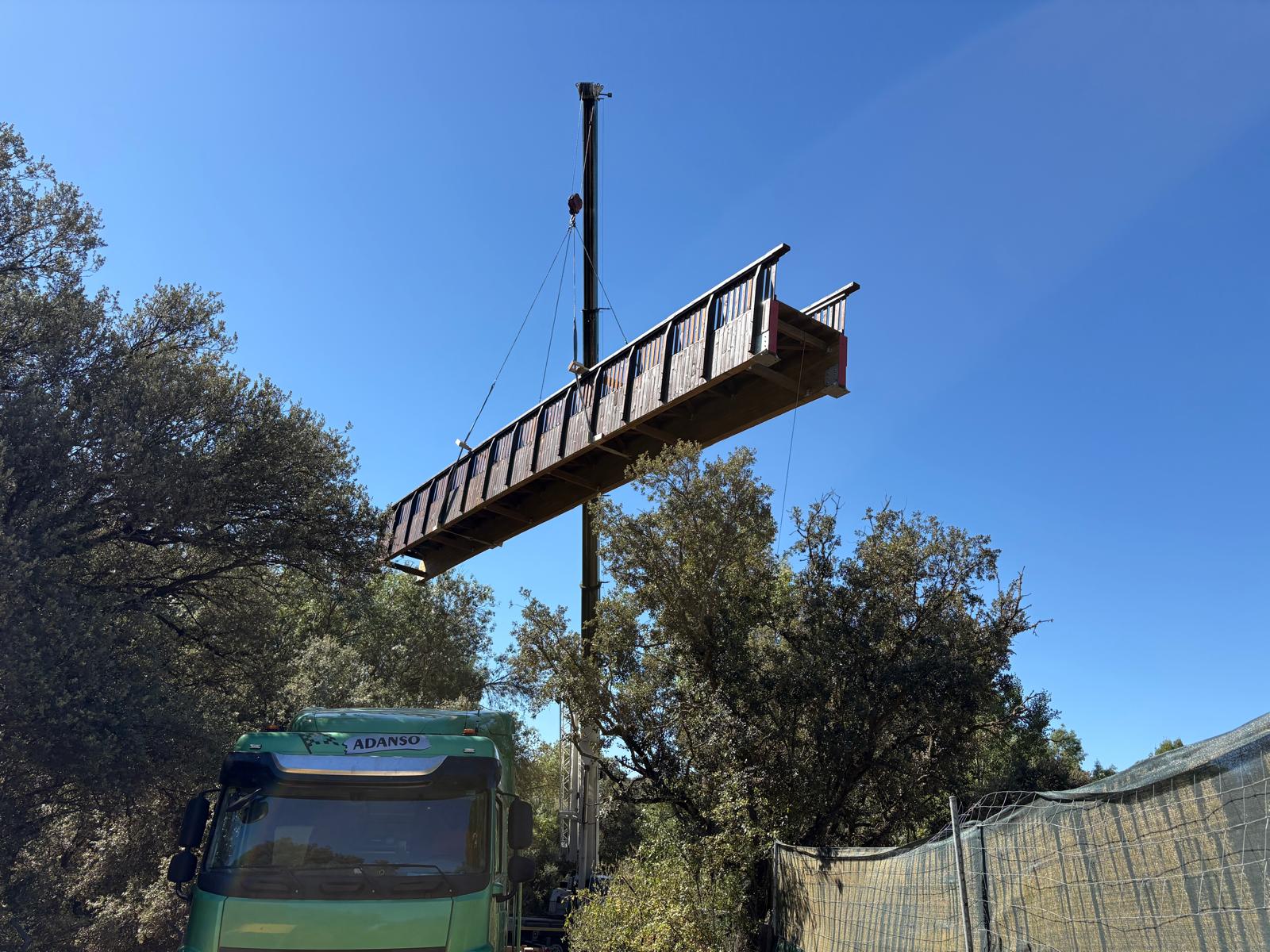 Momento de la instalación de la pasarela de madera sobre el río Aulencia.