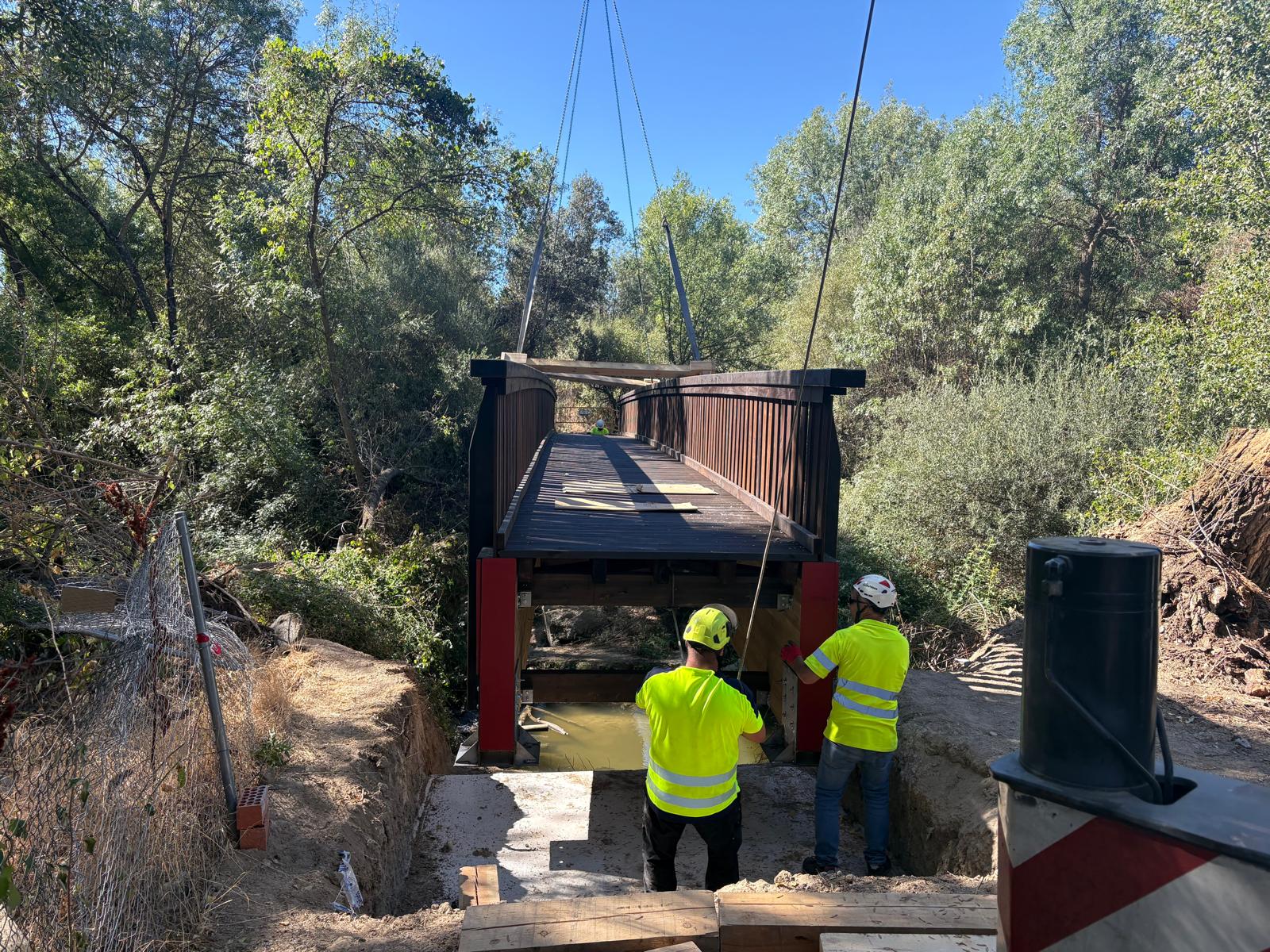 Obreros colocan la estructura de madera sobre el río Aulencia.