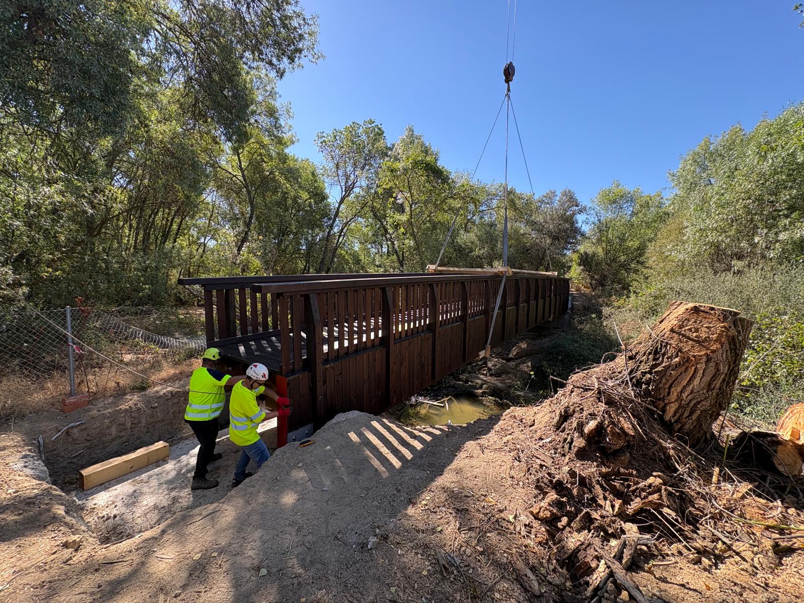 Imagen de la colocación de la pasarela de madera sobre el río.